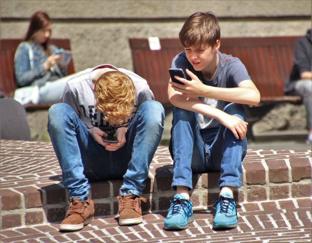 2 young boys on their phones